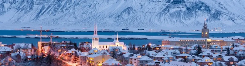 Reykjavík dekket av snø, med fjell i bakgrunnen.