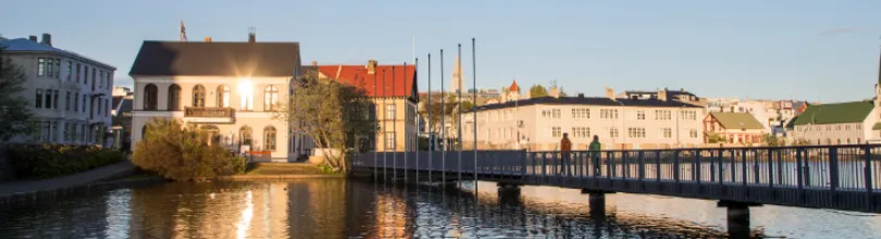 Hus og en gangbro ved Tjörnin i Reykjavík i kveldslys.