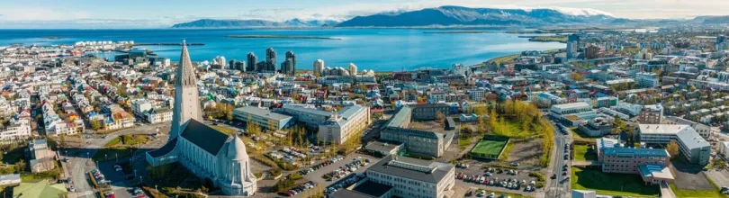 Flyfoto over Reykjavik med Hallgrímskirkja og havet i bakgrunnen.