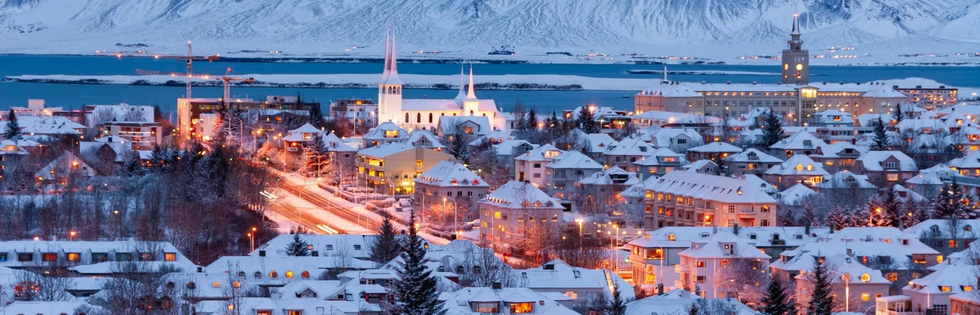Reykjavík dekket av snø, med fjell i bakgrunnen.