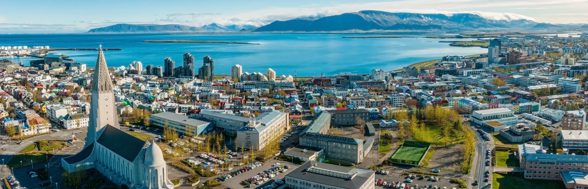 Utsikt over Reykjavík med Hallgrímskirkja, havet og fjellene i bakgrunnen.
